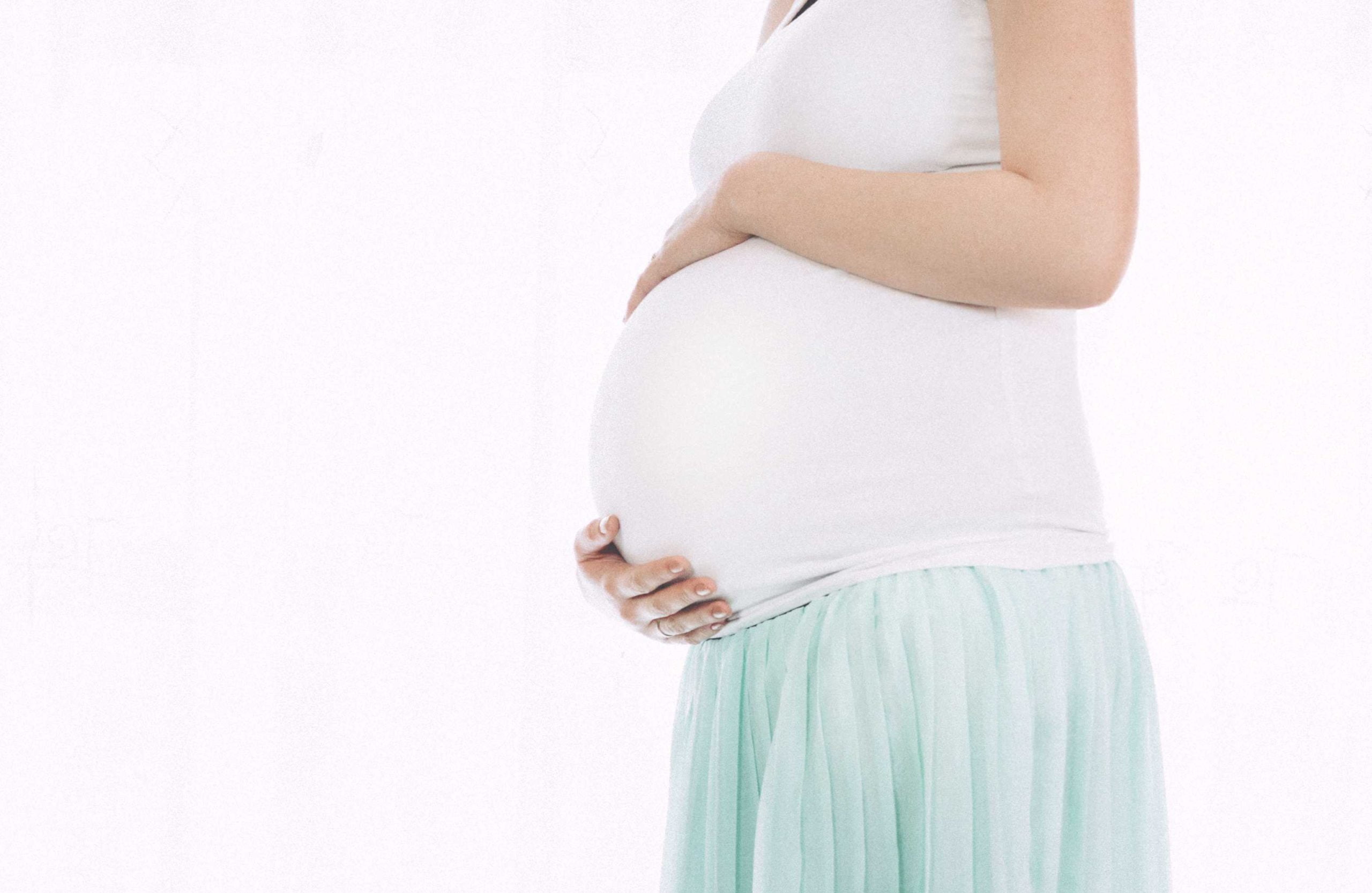 Na sliki je nosečnica, ki se drži za trebuh kjer se nahaja dojenček, slika se uporablja za članek cbd in nosečnost.