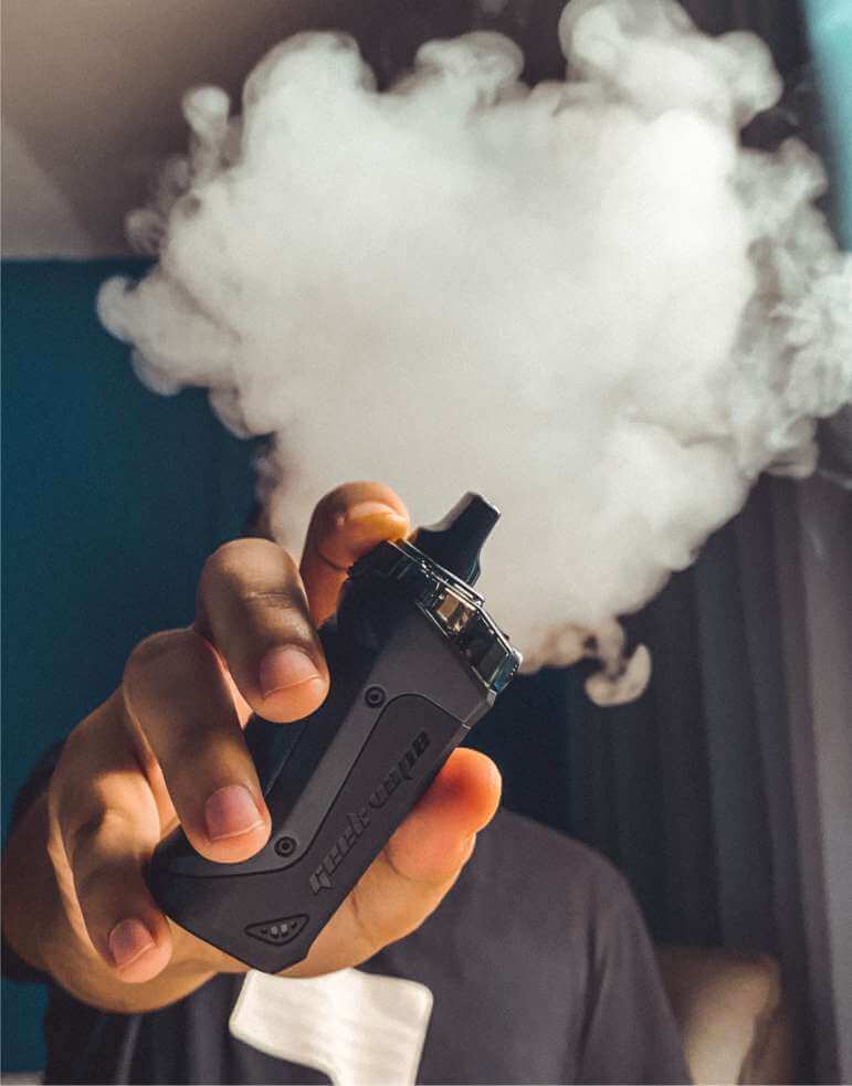 Slika prikazuje vape napravo, ki jo drži moški pred kamero - Odvajanje od kajenja, CBD zmanjša neprijetne simptome