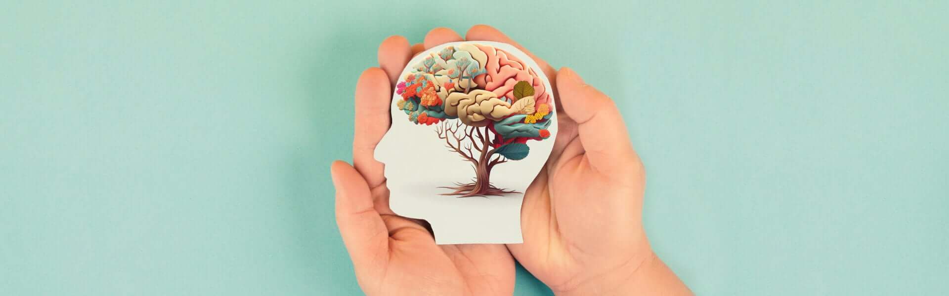 Slika prikazuje roke ki držijo sliko glave ki ima drevo kot možgani.